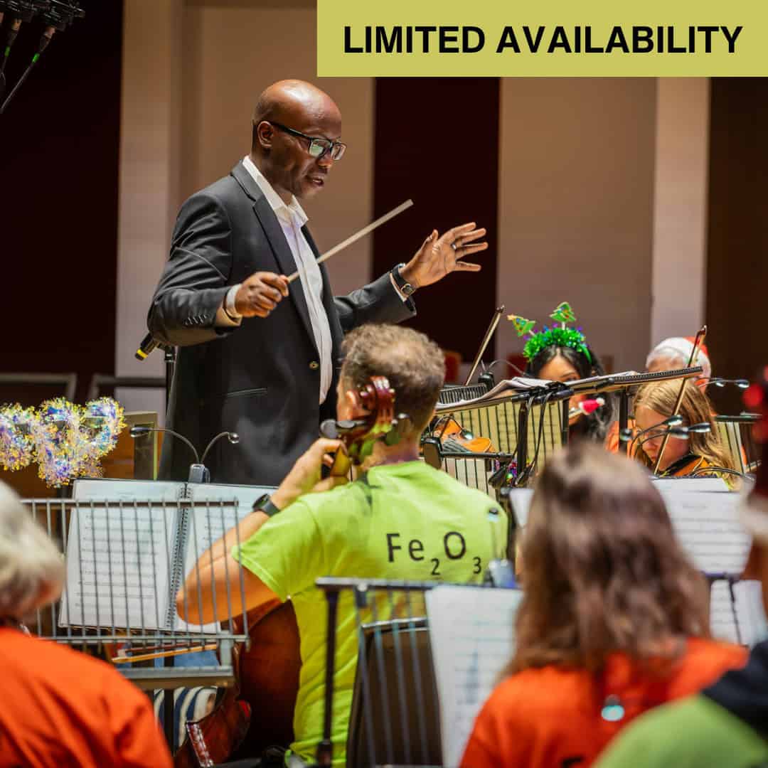 A conductor leads an orchestra wearing coloured t-shirts