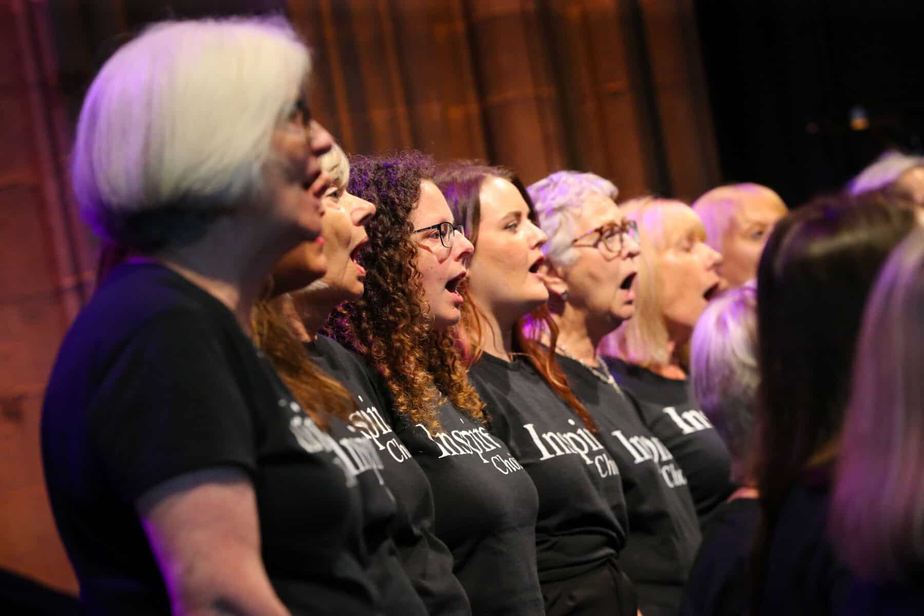 A choir dressed in black stand on stage