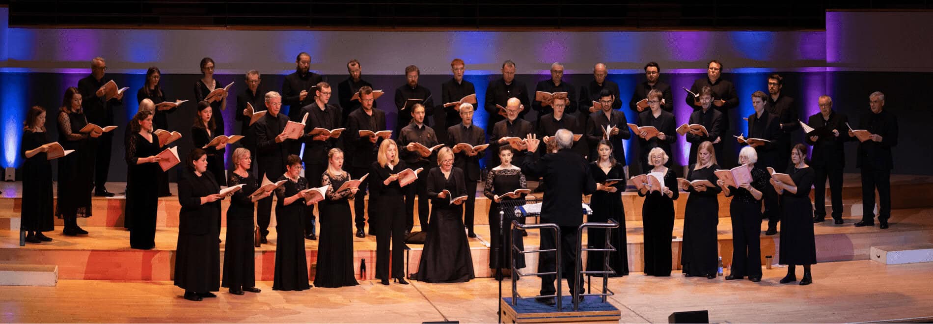 A choir stand on stage in a horseshoe