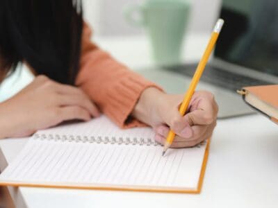 Cropped shot of young female writing her idea concepts on blank notebook