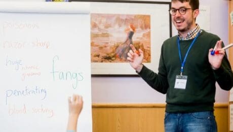 A teacher stands next to a flipchart covered in words about vampires