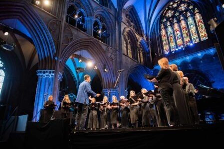 Midlands Choir of the Year A choir stand on stage in Lichfield Cathedral, dressed in black.