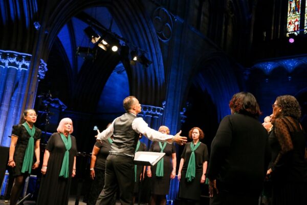 A choir standing on stage led by their conductor