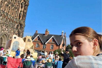 Maja, a teenage girl turns to face the camera in front of outdoor stage