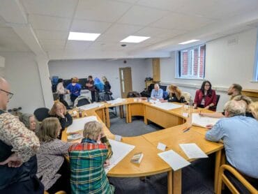A group of people sat around a boardroom table working together