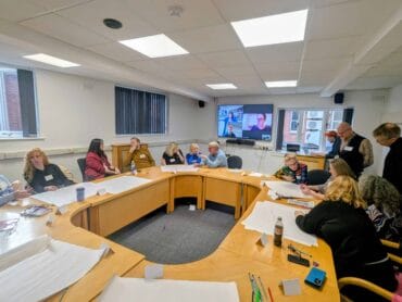 A group of people sat around a boardroom table working together