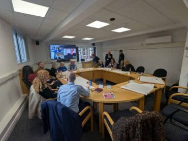 A group of people sat around a boardroom table working together