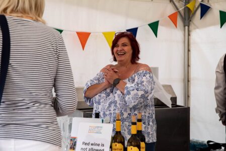 A Festival volunteer smiles as she serves a customer at the bar.