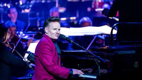 An image of musician Joe Stilgoe playing piano and looking out at the audience